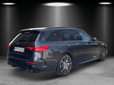 Dunkler Mercedes-Benz Kombi von schräg hinten fotografiert, mit vier Endrohren und sportlichen Leichtmetallfelgen. Fahrzeug steht in einer künstlich ausgeleuchteten Studio-Umgebung.
