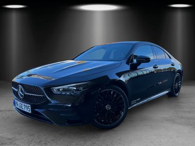Frontansicht eines schwarzen Mercedes-Benz CLA mit sportlichem Design – markanter Diamantgrill mit großem Mercedes-Stern, LED-Scheinwerfer, schwarze AMG-Felgen, getönte Scheiben, Reflektionen der Umgebung auf der glänzenden Lackierung.