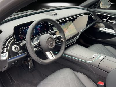 Innenraum eines Mercedes-Benz mit volldigitalem Widescreen-Cockpit, Multifunktionslenkrad, Ambientebeleuchtung und hochwertiger Lederausstattung in Rautensteppung – moderne, luxuriöse Atmosphäre.