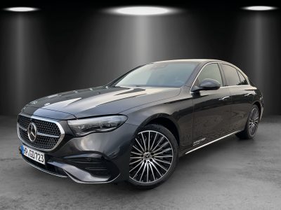 Front- und Seitenansicht einer schwarzen Mercedes-Benz Limousine mit markantem Diamantgrill, 4MATIC-Antrieb und AUTOWELT EBERT Branding – ausgeleuchtet in einem Studio mit Spotlights.