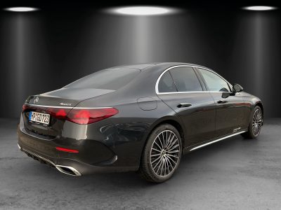 Heck- und Seitenansicht einer schwarzen Mercedes-Benz Limousine mit 4MATIC-Antrieb, edlen Leichtmetallfelgen und AUTOWELT EBERT Branding – Studiohintergrund mit Spotlights.