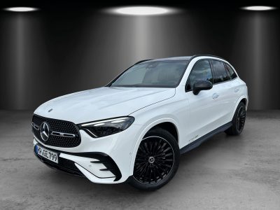 Front- und Seitenansicht eines weißen Mercedes-Benz SUV mit AMG-Line, schwarzen Leichtmetallfelgen, LED-Scheinwerfern und Panoramadach im Studio-Setting.