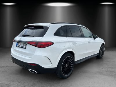 Heck- und Seitenansicht eines weißen Mercedes-Benz SUV mit 4MATIC-Antrieb im Studio, schwarze AMG-Felgen, getönte Scheiben und dezentes Chrom-Design.