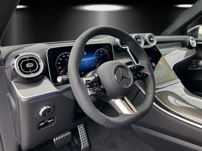 Modernes Mercedes-Benz Interieur mit AMG-Lenkrad, voll digitalem Cockpit und großem Touchscreen-Display. Hochwertige Materialien, Ambientebeleuchtung und sportliche Designelemente sorgen für ein luxuriöses Fahrerlebnis.