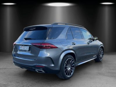 Heckansicht eines grauen Mercedes-Benz GLE SUV mit getönten Scheiben, AMG Line Ausstattung, silbernen Endrohrblenden und Leichtmetallrädern – Fahrzeug steht im Studio mit Spotbeleuchtung.