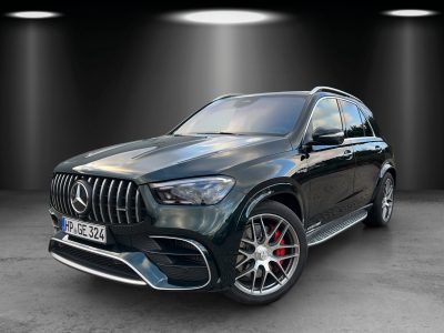 Dunkelgrüner SUV in Studiobeleuchtung, schräg von vorn links fotografiert, mit markanter Frontpartie, vertikalem Kühlergrill, roten Bremssätteln und großen Leichtmetallfelgen.