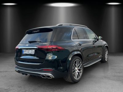 Schwarzer SUV in beleuchteter Studioumgebung, fotografiert schräg von hinten rechts, mit sportlicher Vierrohr-Auspuffanlage und glänzenden Leichtmetallfelgen.